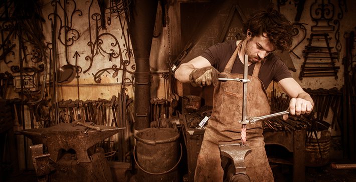 Ironworker forging hot iron in workshop