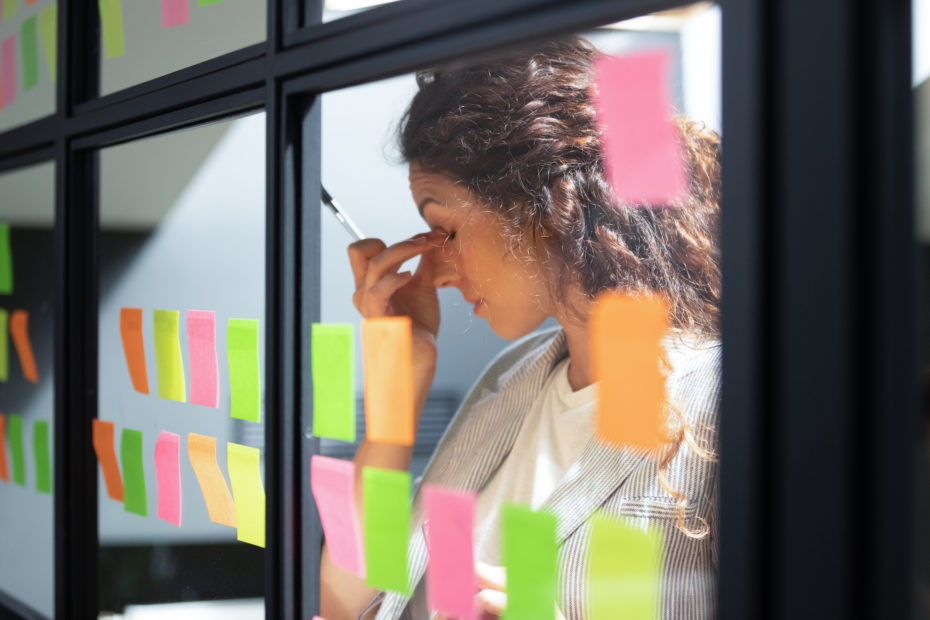 Tired businesswoman touching nose bridge, working with sticky papers