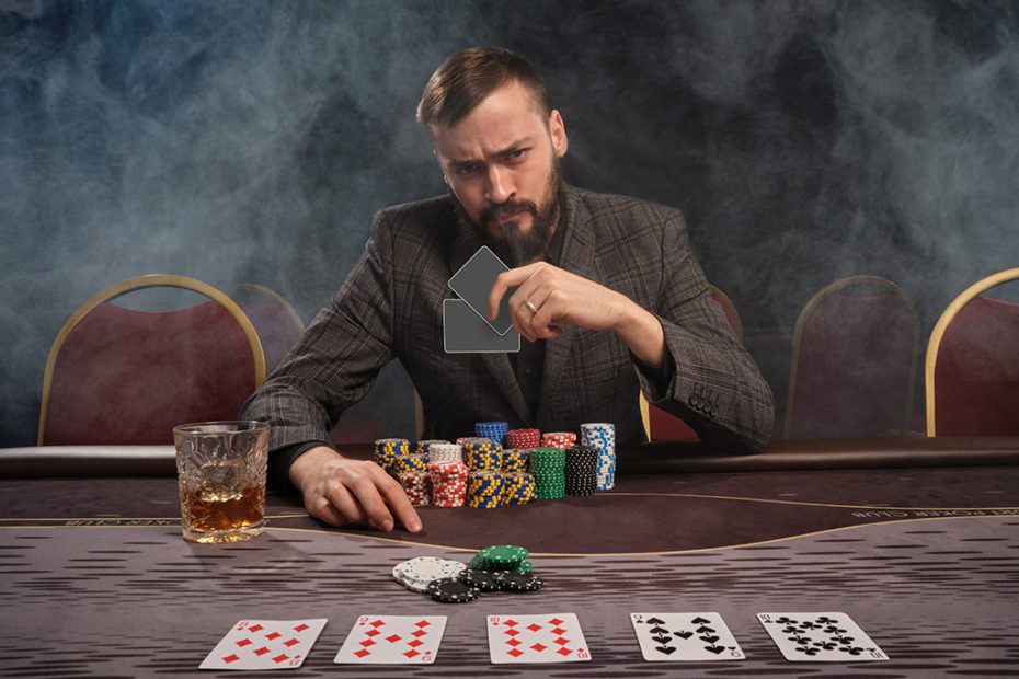 Handsome bearded man is playing poker sitting at the table in casino.