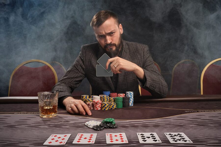 Handsome bearded man is playing poker at the table in casino.