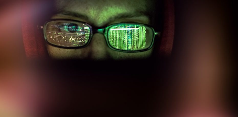 hacker at computer data reflecting in eyeglasses