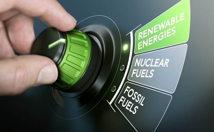 Man turning an energy transition button to switch from fossil fuels to renewable energies. Composite image between a hand photography and a 3D background.