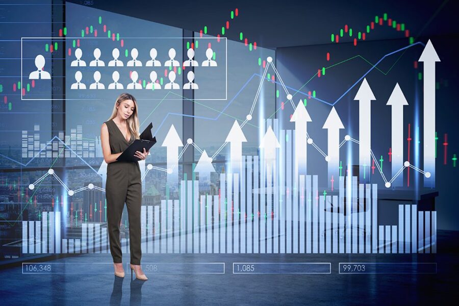 Business woman wearing beige dress holds clipboard.  Financial chart and bar chart in the foreground.  Office workplace with skyscraper in New York City in the background.  Concept of successful trading