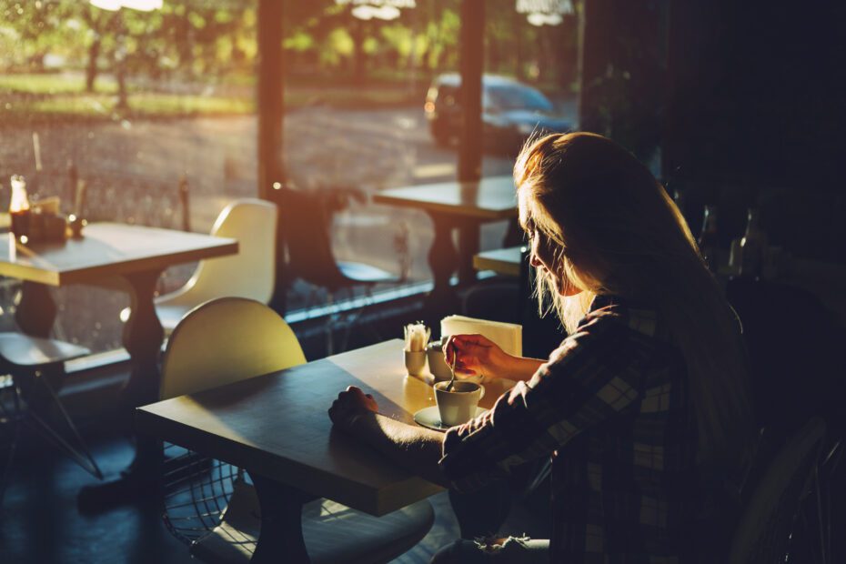 Young female student sitting in modern coffe shop. Sunset.Woman