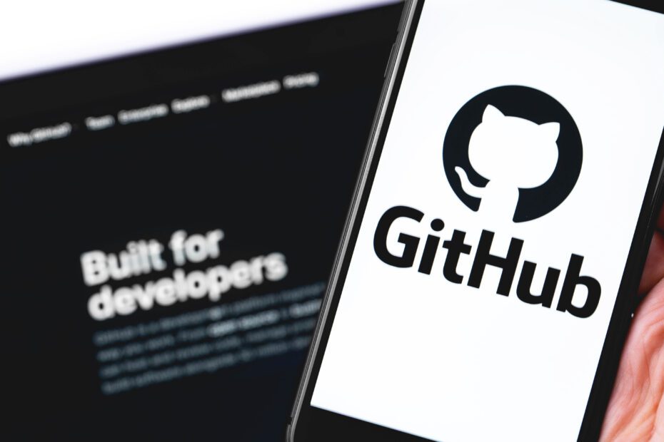 GitHub logo on the screen smartphone and notebook closeup. GitHu